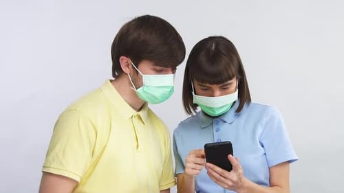 Woman Showing Man Something on Phone Wearing Masks
