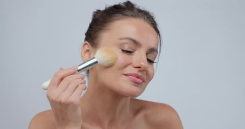 Beautiful Woman Applying Makeup with Brush