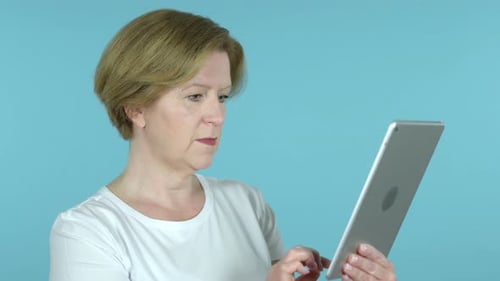 Senior Woman Celebrates News on Tablet Device