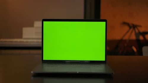 Laptop Computer Showing Green Chroma Key Screen Stands on a Desk in Living Room