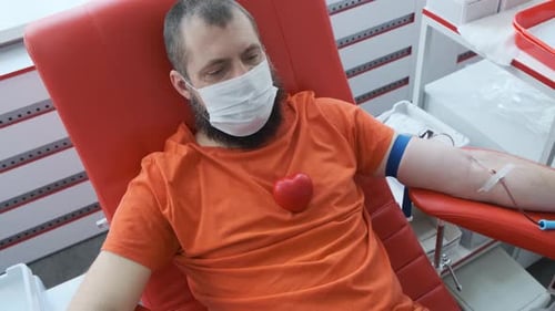 Bearded Adult Donating Blood in Hospital Chair