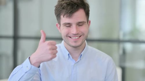 Young Man Gives Thumbs Up in Office Setting
