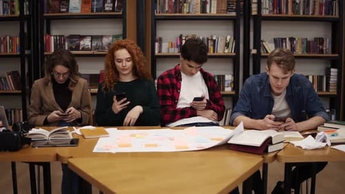 Group of Four University Students Two Males Two Females Sitting at the Table Together During Break