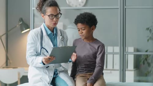 African American Kid Talking with Female Doctor on Consultation in Clinic