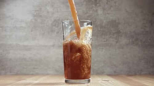 Dark Brown Beverage Poured Into a Glass With Ice