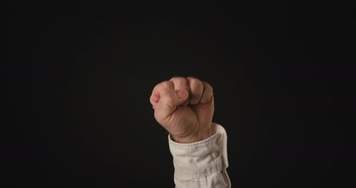 Hand Forms a Fist Against Black Background