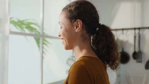 Smiling Woman Holding Bowl of Fresh Fruit Indoors
