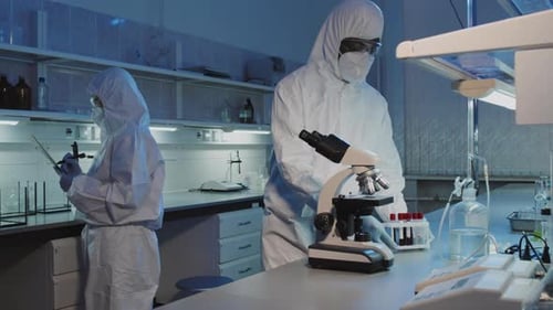 Scientists Work with Microscope in Medical Laboratory