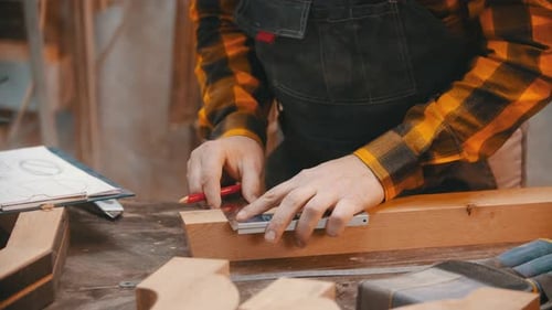Craftsman Measuring Wood with Pencil in Workshop