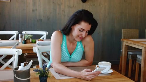 Woman Using Phone in Cafe During the Day