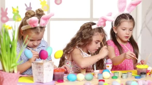 Delightful Children Painting Easter Eggs with Bunny Ears