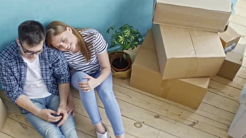 Loving Couple Sitting on Floor of New Flat