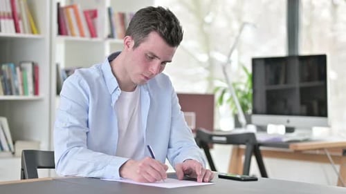 Man Writing at Desk in Bright Room
