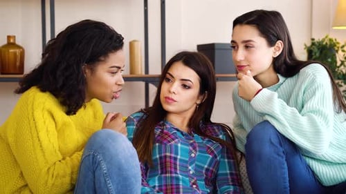 Filles intrigantes assises dans le salon et commérages
