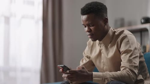 Young Man Uses Mobile Phone Indoors