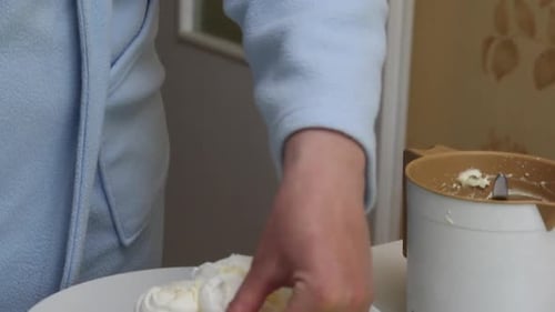 A Woman Prepares A Cake Count Ruins From Meringue. Folds Meringues On A Plate, Smeared With Cream