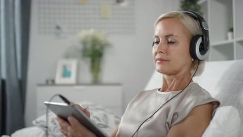 Woman Relaxing on Couch with Tablet and Headphones