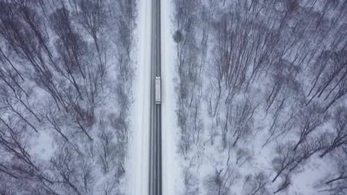 Blick von oben auf den Verkehr auf einer von Winterwald umgebenen Straße