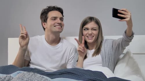 Glückliches Paar im Bett macht Selfie mit Smartphone-Foto