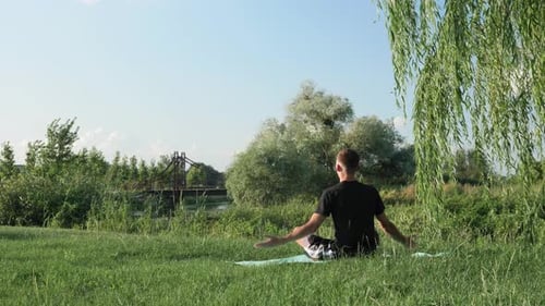 Man Does Yoga in Grassy Rural Landscape