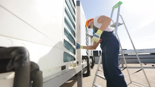 Young Engineer Repairing Commercial Refrigeration Unit on Rooftop