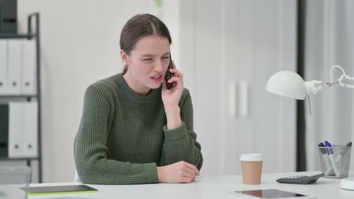 Young Woman Angrily Talking on Phone in Office