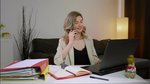 Businesswoman Working at Computer While Talking on Phone