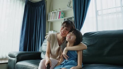 Woman and Child Smiling Together on Couch Indoors