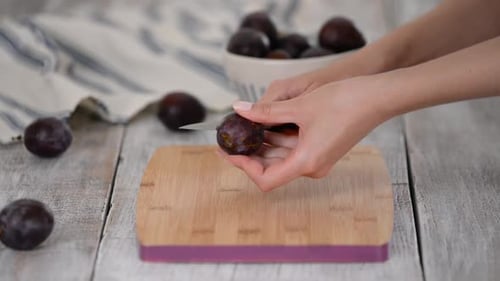 Female Hands Cut the Black Plum and Remove the Putamen.
