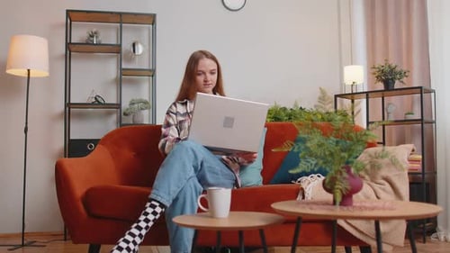 Young Woman Using Laptop on Orange Couch