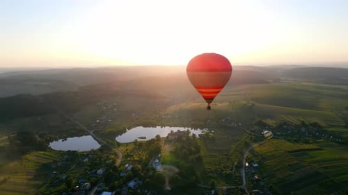 Hot Air Balloons Fly Over Green Landscape at Sunrise