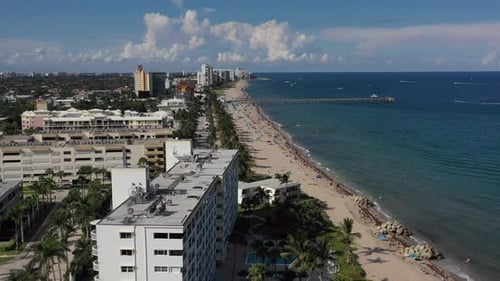 aerial following buildings on the coastal side of a beach