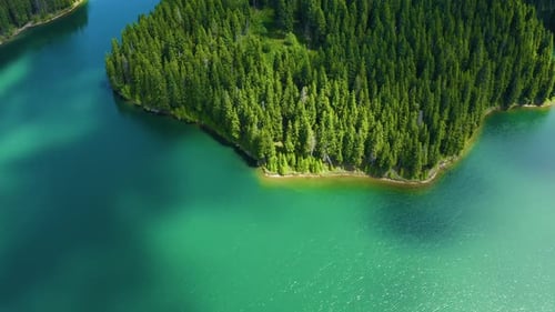 Mountain lake island with turquoise water and green trees. Reflection in the water.