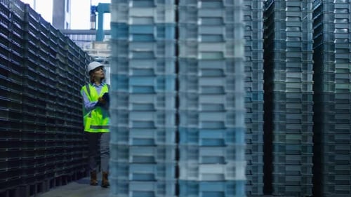 Female Storehouse Employee Inspecting Blue Supply Crates Checking Delivery