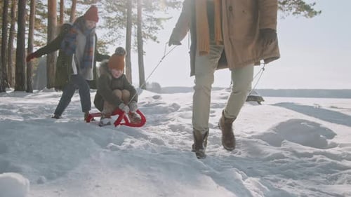 Father Pulling Daughter on Sled in Forest