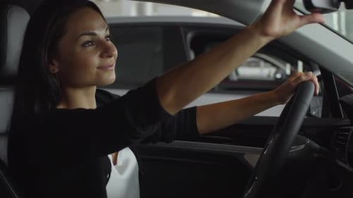 Cheerful Woman Enjoying Car Interior in Auto Showroom