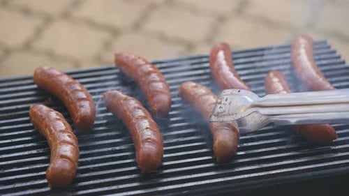 Man Flips Sausages on the Grill