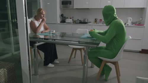 Woman and Figure in Green Bodysuit Cutting Orange