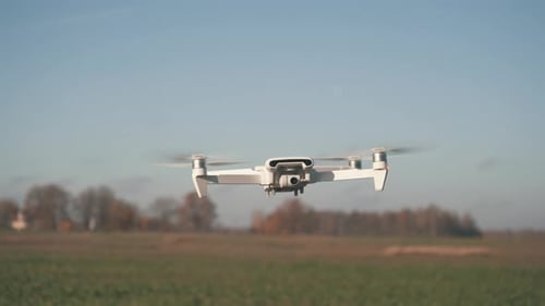 White Drone Flying on Nature Background. Drone Hanging in Air Flying Helicopter Dron Remote Control