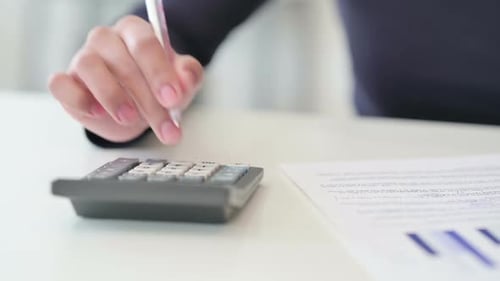 Hand Close Up of African Woman Using Calculator and Writing