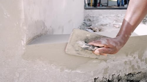 Manual Worker's Hand Plastering Wall Using Hand Trowel At Construction Site. close up, slow motion