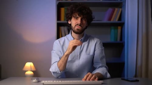POV Shot of Disgruntled Young Man Typing Online Message on Wireless Keyboard Looking at Camera