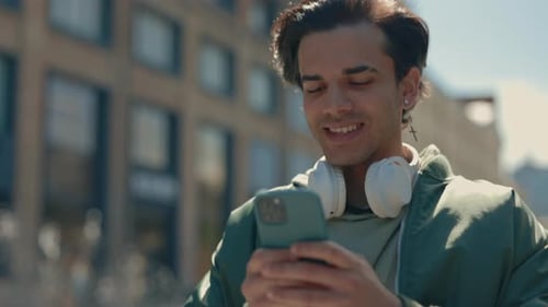 Positive Man Using Mobile While Walking on Street