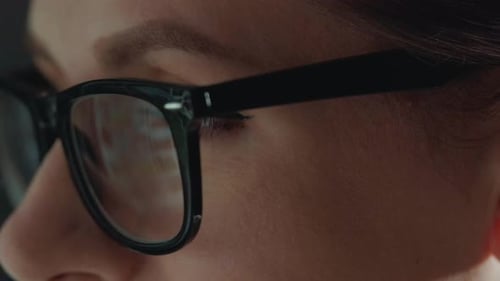 Eyes Behind Glasses Reflecting Data on a Screen