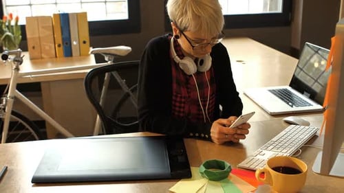 Woman Using Phone at Creative Workplace Desk