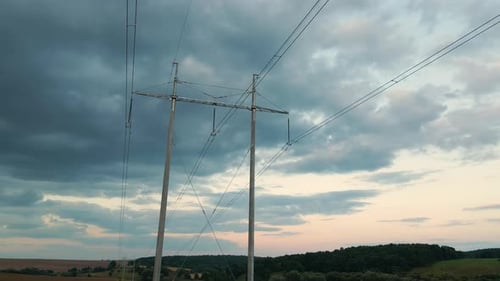 Dark Silhouette of High Voltage Tower with Electric Power Lines at Sunset