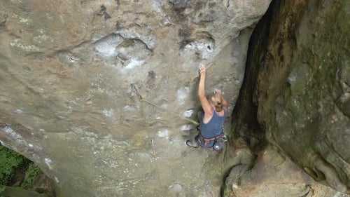 Determined Senior Woman Climber Clambering Up Steep Wall of Rocky Mountain