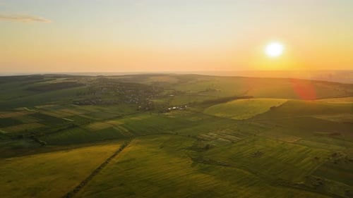 Aerial Landscape View of Green Cultivated Agricultural Fields with Growing Crops and Distant Village