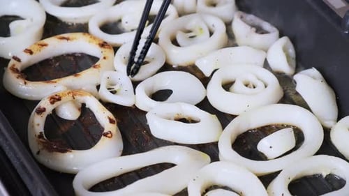 Cooking squid rings in a frying pan. Rings of calamari are frying in grill pan in kitchen