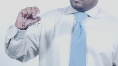 Man Writes August with Pen on Surface